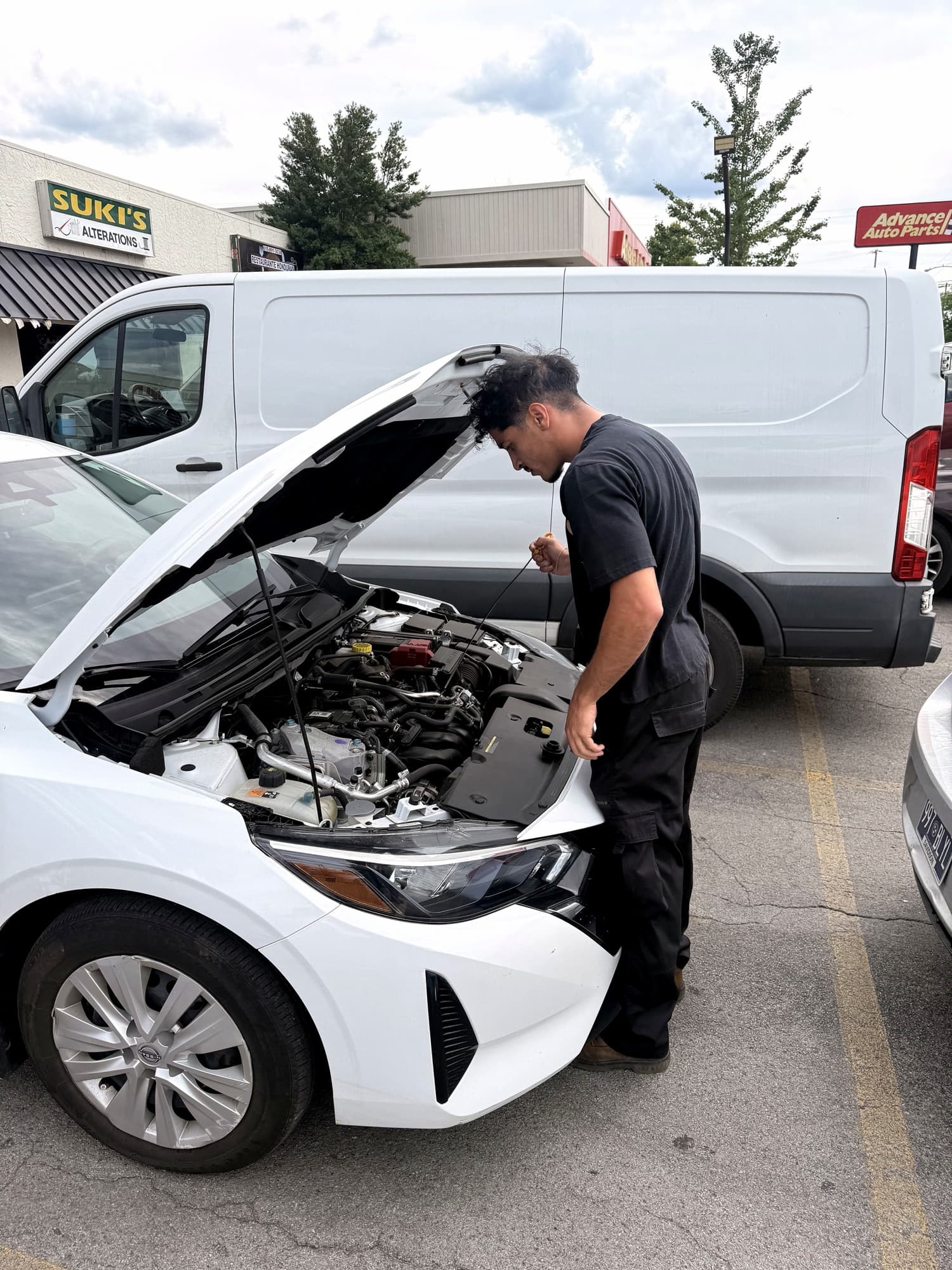 Omar Almasri checking a customer's vehicle beside the MT Mobile Auto Repair service van
